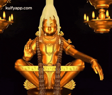 a gold statue of a deity with candles behind it