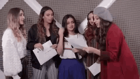 a group of young women are standing next to each other in a room holding papers .