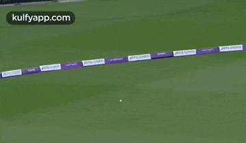 a group of men are playing a game of cricket on a field and one of them is laying on the ground .