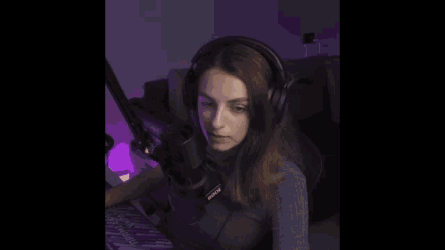a woman wearing headphones and a rode microphone is smiling