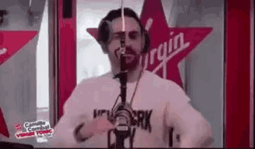 a man with a beard is dancing in front of a microphone in a radio station .