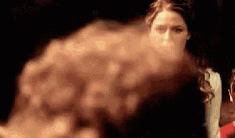 a woman is standing in a dark room with smoke coming out of her face .