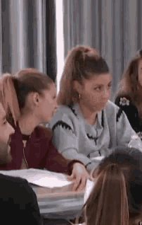 a group of people are sitting at a table in a room talking to each other .
