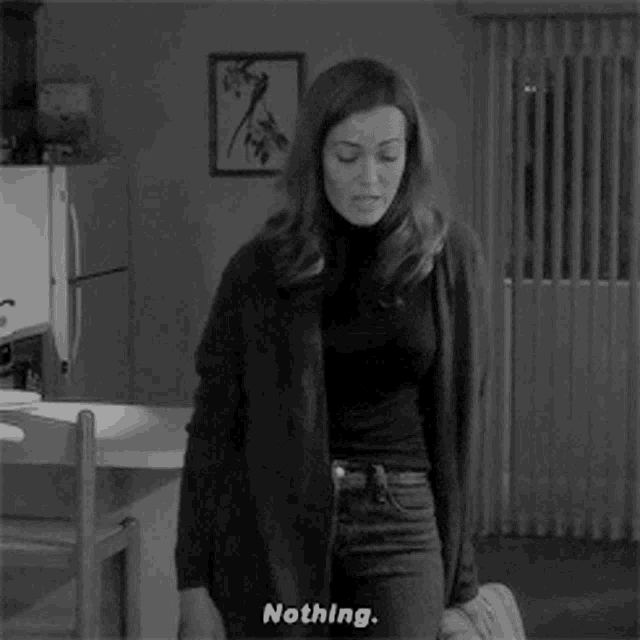 a woman in a black and white photo is standing in a kitchen and saying nothing .