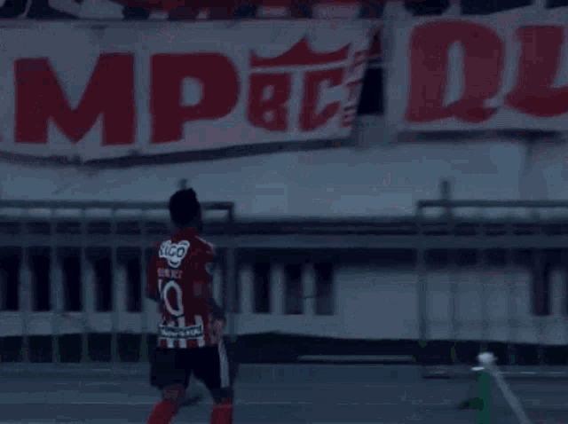 a soccer player wearing a number 10 jersey stands in front of a banner