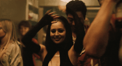 a woman with a necklace on her neck is dancing in a crowd of people