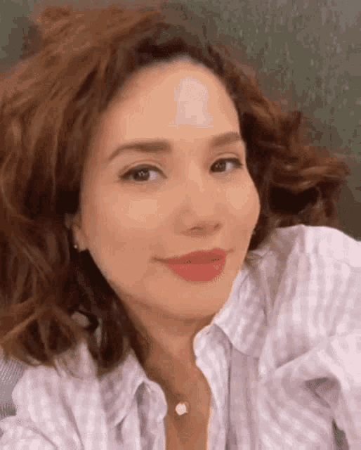 a close up of a woman taking a selfie with her hair in the air .