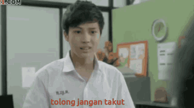 a boy in a white shirt with tong jangan takut written in red