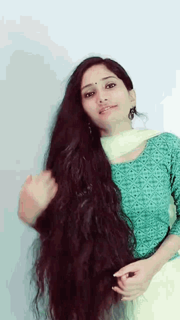 a woman with very long hair is wearing a green top and a white dupatta