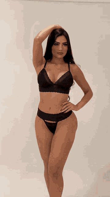 a woman in a black bra and thong is standing with her hand on her hip