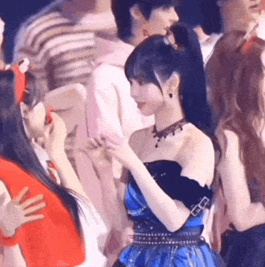 a girl in a blue dress is talking to another girl in a crowd .