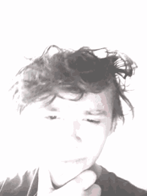 a young boy with messy hair is making a funny face with his hand on his chin .