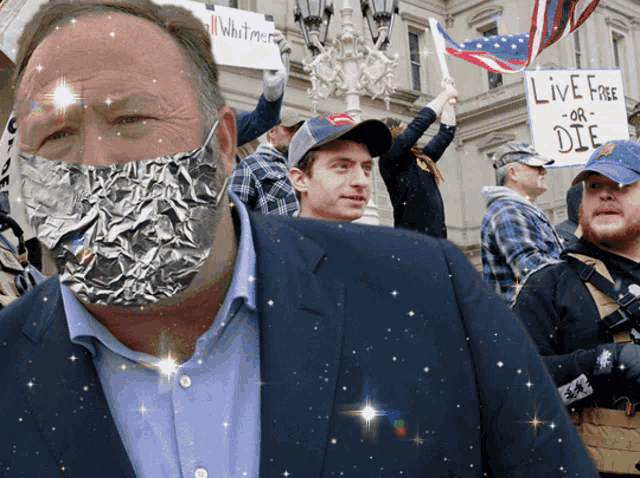 a man wearing a tin foil mask holds up a sign that says " live free or die "