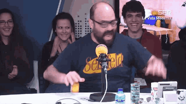 a man wearing a shirt that says seven eleven is talking into a microphone