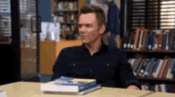 a man sits at a table with a stack of books on it