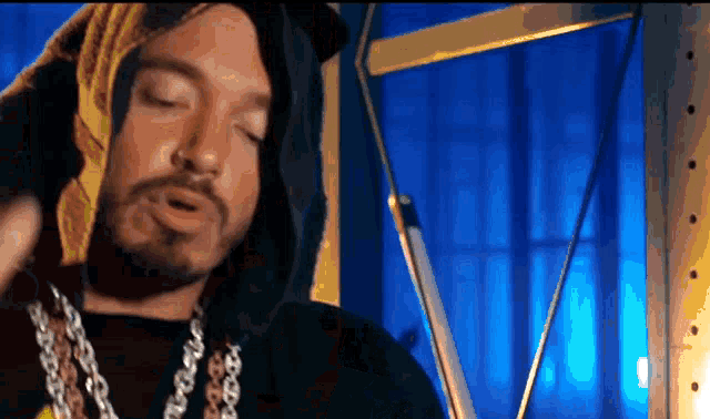 a man with a beard wearing a hooded shirt and chains
