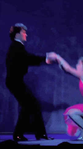 a man in a tuxedo and a woman in a pink dress are dancing together