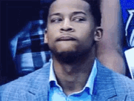 a man in a suit and blue shirt is looking up at something .