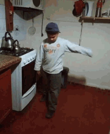 a young boy is dancing in a kitchen wearing a shirt that says jeepy