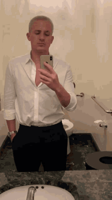 a man taking a selfie in a bathroom with his phone