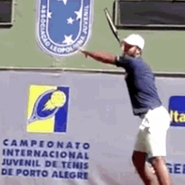 a man is swinging a tennis racquet in front of a sign that says ' a ' on it