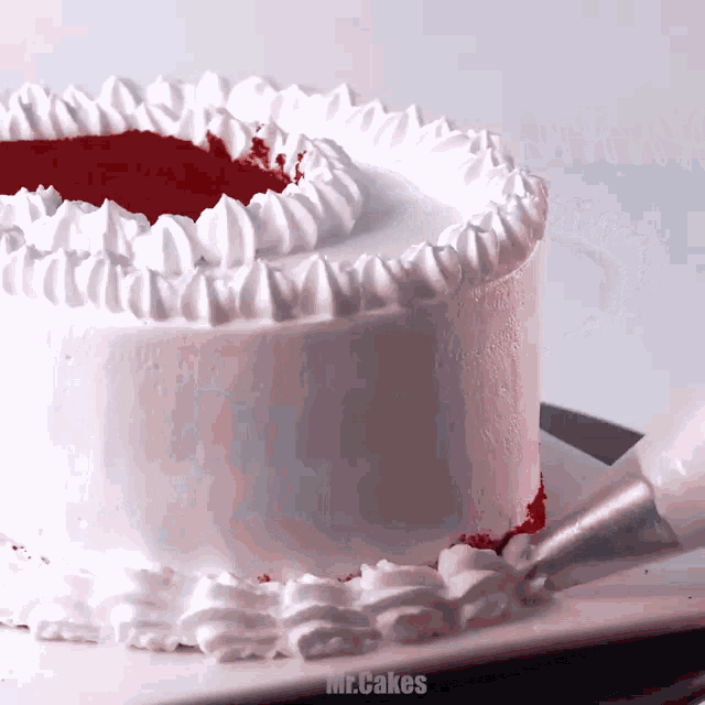 a cake with white frosting and red filling is being decorated by mr. cakes