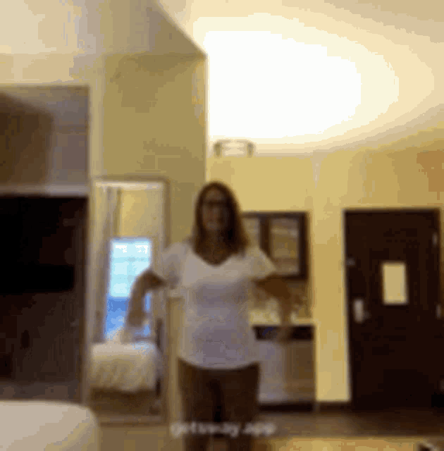 a woman in a white shirt and shorts is standing in a room