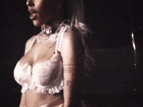 a woman with a tattoo on her arm is wearing a white bra .