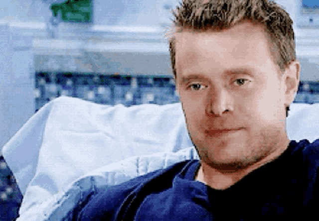 a man is laying in a hospital bed and looking at the camera .
