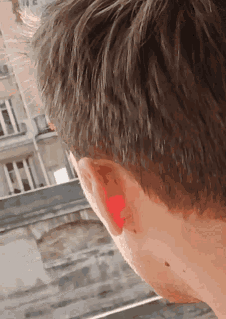 a close up of a man 's ear with a red spot in it