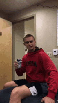 a man in a red jordan sweatshirt holds a can of soda