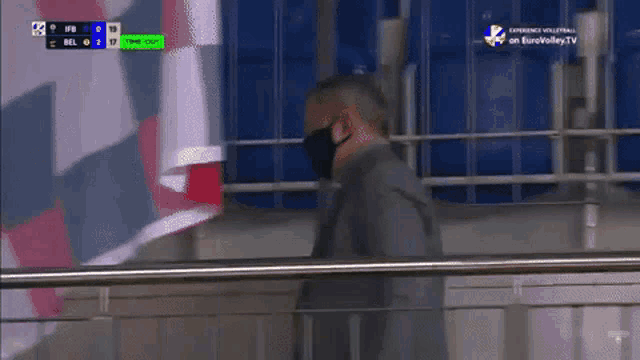 a man wearing a mask stands in front of a scoreboard that says eurovolleytv