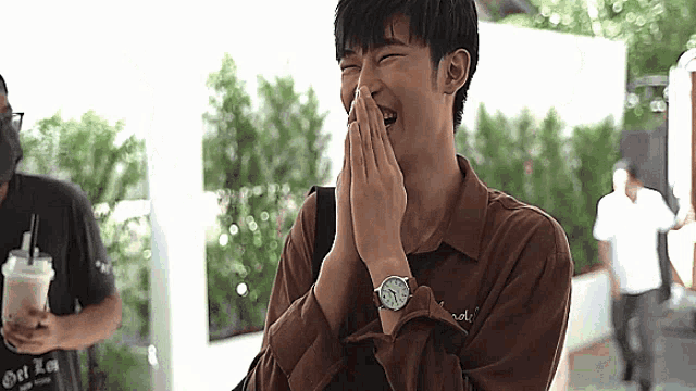 a man wearing a watch is laughing while covering his mouth