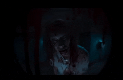 a zombie with blood on his face is holding a knife in his hand .
