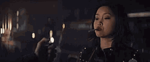 a woman is smoking a cigarette in a dark room with a blurry background