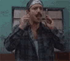 a man with a mustache and a bandana on his head is making a funny face .