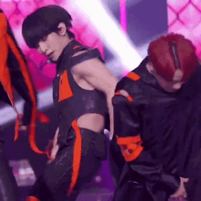 a man in a black and orange outfit is dancing on stage .