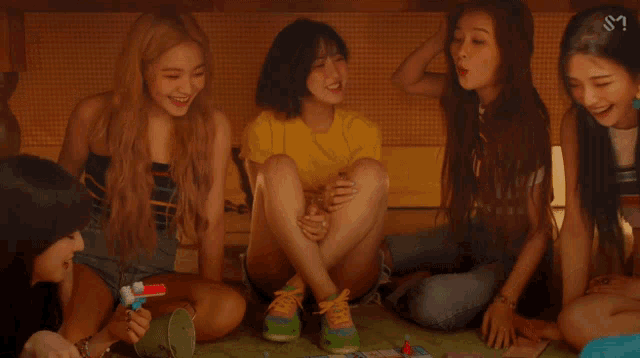 a group of girls sit on the floor playing a game