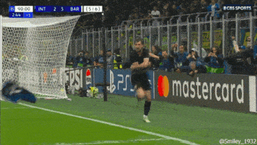 a man running on a soccer field with a mastercard banner behind him