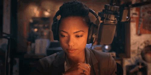a woman wearing headphones is sitting in front of a microphone in a room .