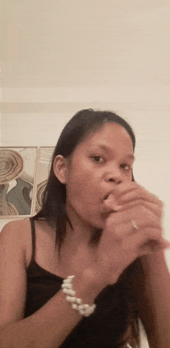 a woman wearing a black tank top and a white pearl bracelet