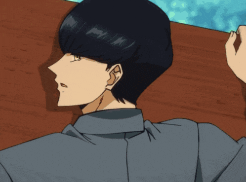 a man with black hair and a blue shirt is laying on a wooden table
