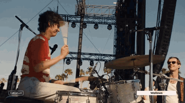 a man playing a drum set with the word wallows on the bottom
