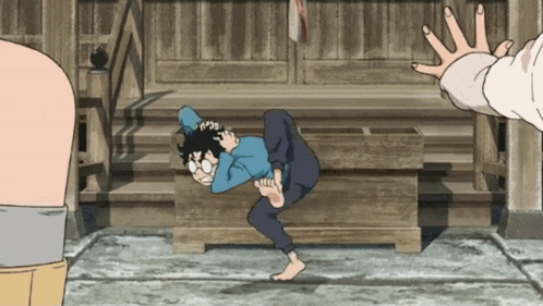 a man in a blue shirt is doing a handstand in front of a wooden table