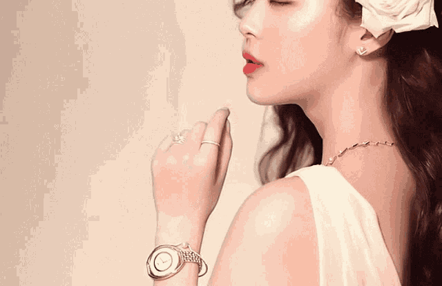 a woman in a white dress with a flower in her hair has a ring on her finger
