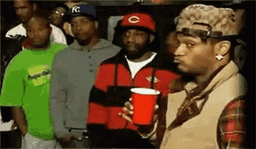 a group of men are standing next to each other in a room . one of the men is holding a red cup .