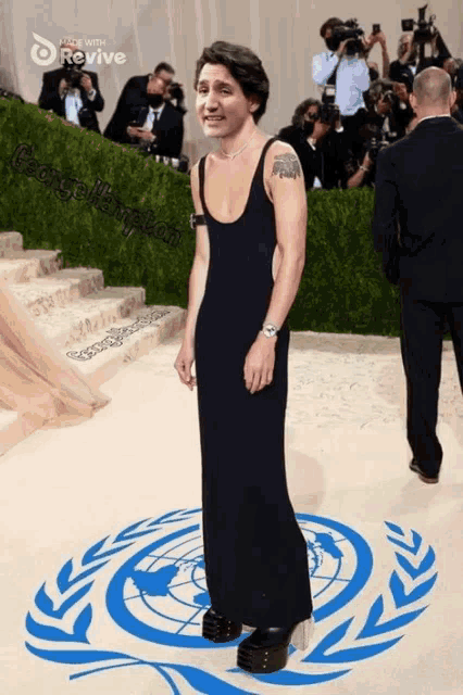 a man in a black dress stands in front of a united nations logo on the floor