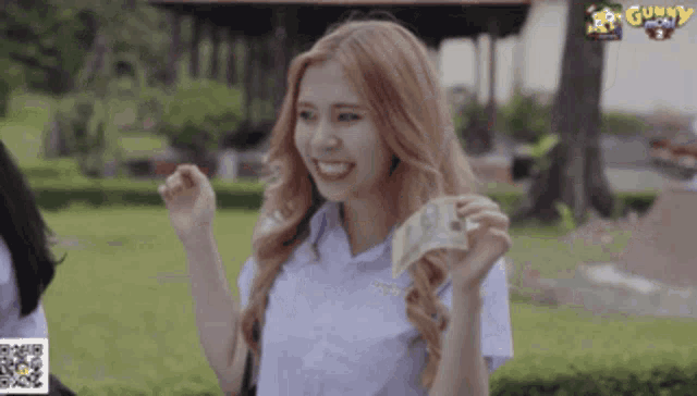 a girl in a white shirt is holding a stack of money