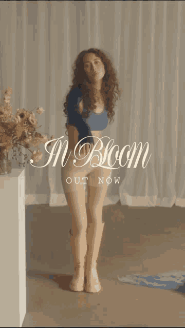 a woman blowing a kiss with the words in bloom out now behind her