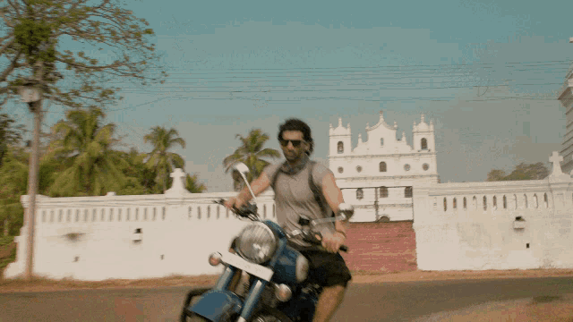 a man is riding a blue motorcycle on a street in front of a white building